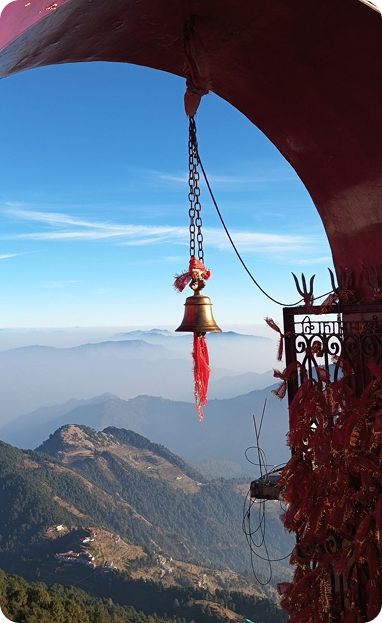 Himalayan valley framing an arched view of a traditional temple bell